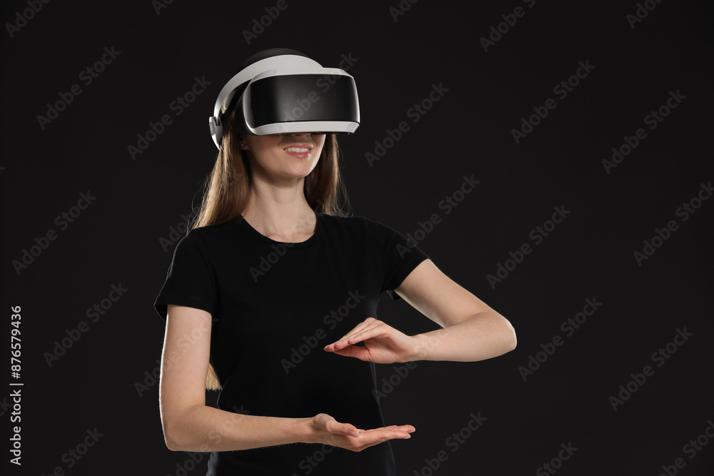 Smiling woman using virtual reality headset on black background, space for text Smiling woman using virtual reality headset on black background, space for text