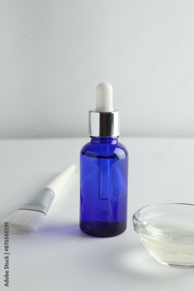 Bottle of chemical peel, bowl with liquid and brush on light background. Peeling procedure Bottle of chemical peel, bowl with liquid and brush on light background. Peeling procedure