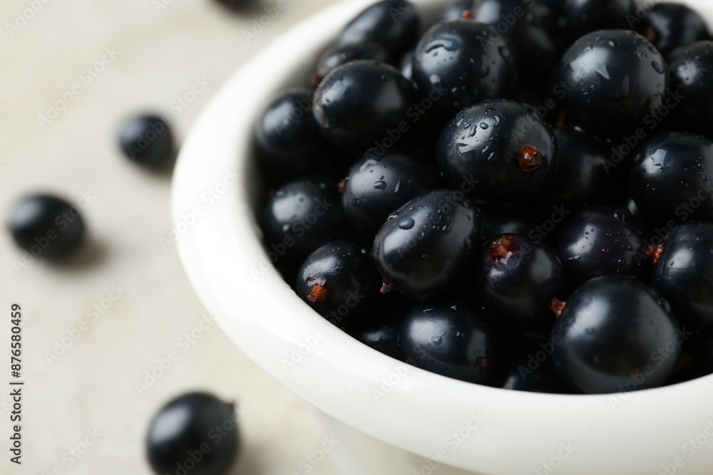Ripe black currants in bowl on light table, closeup