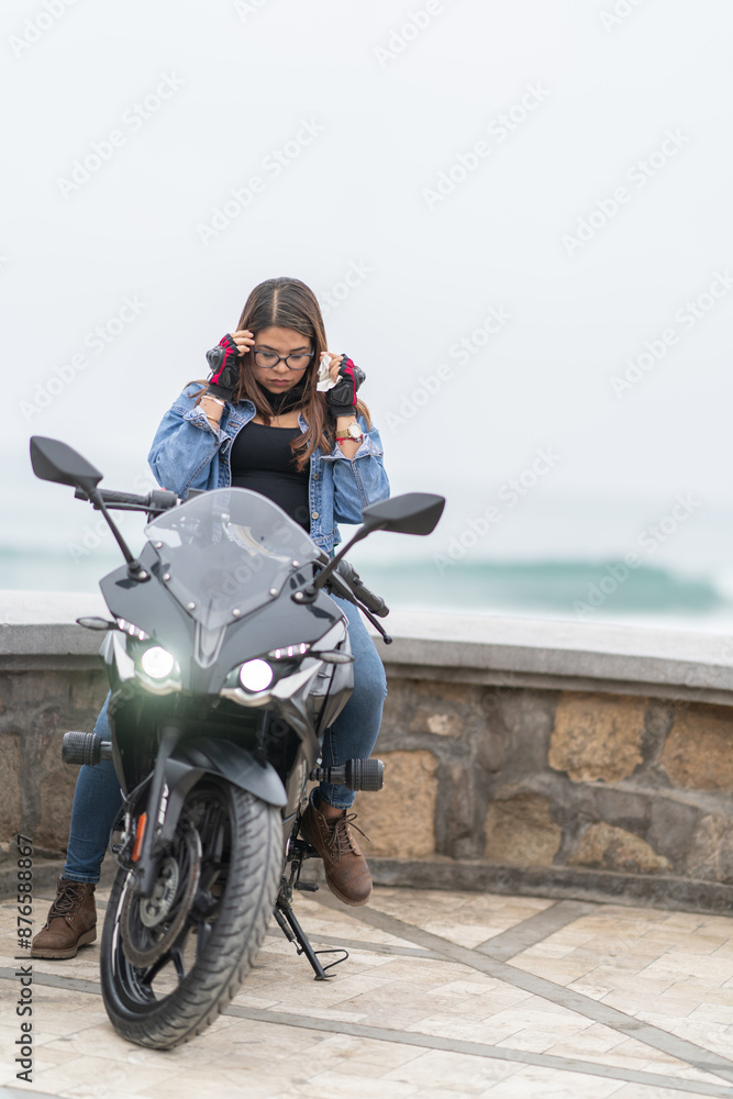 Woman putting on glasses sitting on a motorbike