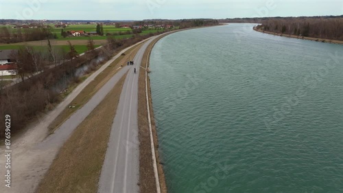 Wallpaper Mural Cyclists ride on an embankment bicycle path along River Innnear Rosenheim, Bavaria, Germany. Am Innradweg bei Rosenheim. Gravel bike path along a wide river in Deutschland. Cycling in upper Bayern.  Torontodigital.ca