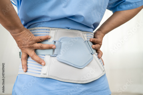 Asian woman patient wearing back pain support belt for orthopedic lumbar with walker.