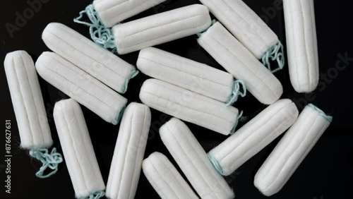 Many tampons rotating, overhead view of standard white tampons on dark background. photo