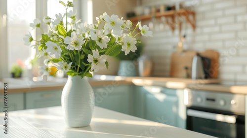 Vase with fresh spring flowers on dinning table on the background of modern kitchen in Scandinavian interior style. Light white blue colors