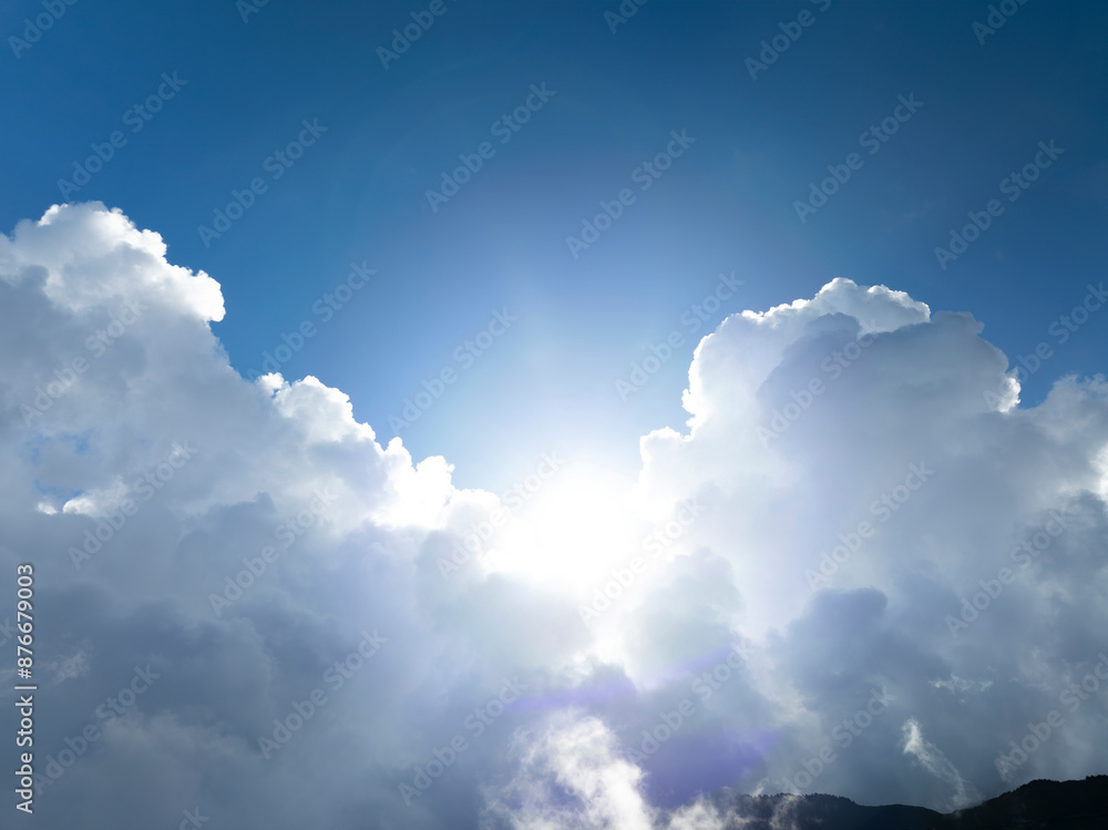 Fototapeta premium The sun shining through the puffy clouds above mountain