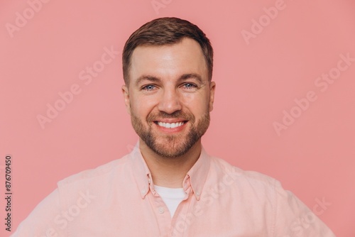 Cute smiling unshaven man in pink shirt posing isolated on pink background