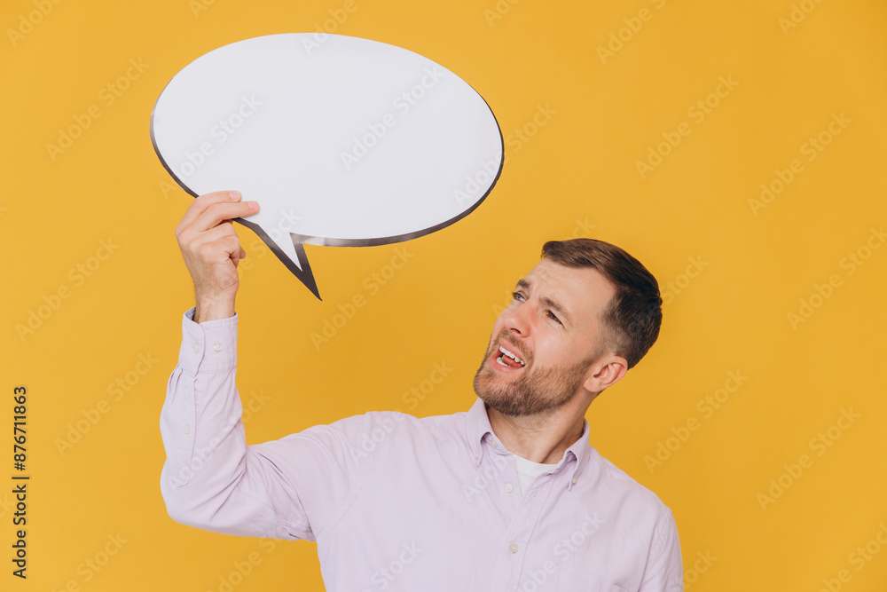 Cute unshaved man holding empty blank cloud, speech bubble promotional content isolated on yellow background studio portrait. Cute unshaved man holding empty blank cloud, speech bubble promotional content isolated on yellow background studio portrait.