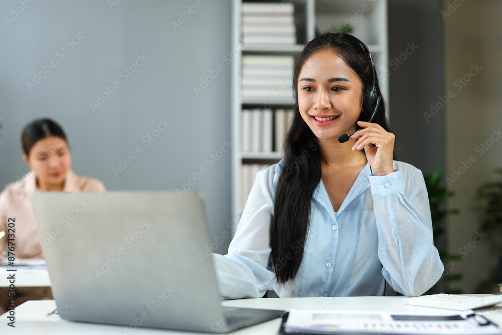 Asian businesswoman employee or executive using laptop computer and wearing headset video call explaining online meeting or online training. Document work in the office. Asian businesswoman employee or executive using laptop computer and wearing headset video call explaining online meeting or online training. Document work in the office.