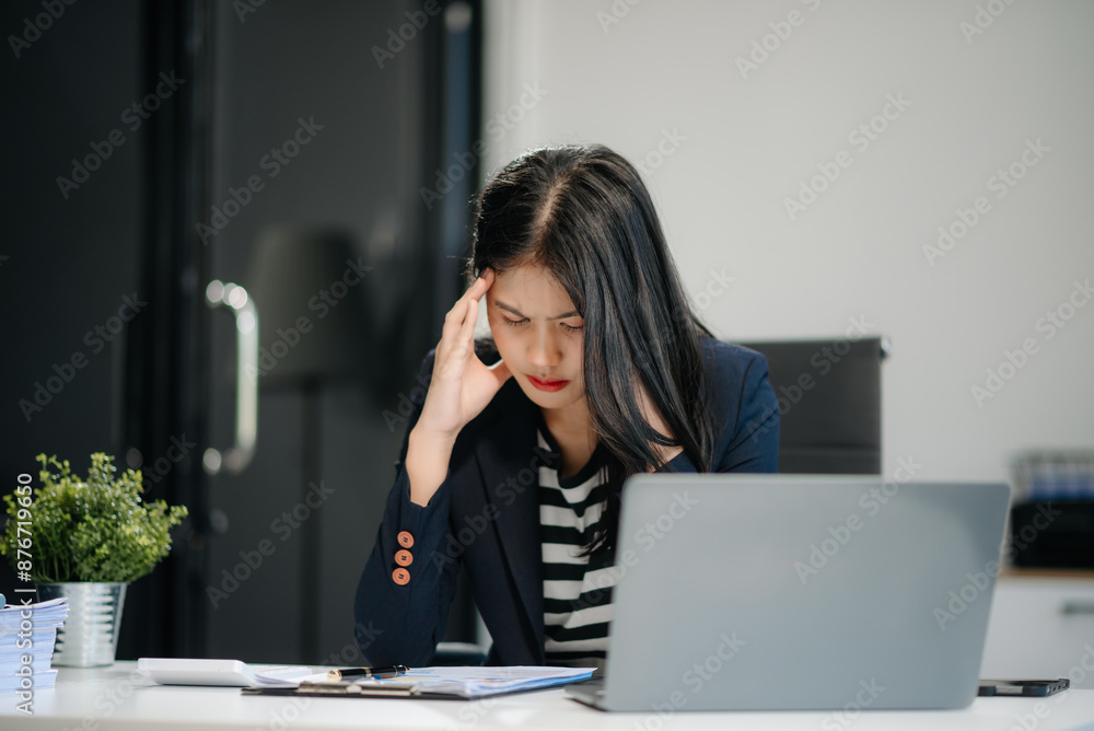 Asian business woman is stressed, bored, and overthinking from working on a tablet Asian business woman is stressed, bored, and overthinking from working on a tablet