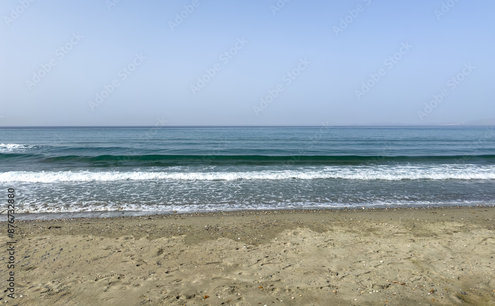 Sandy beach at Greek island. Ripple sea touches wet sand, blue sky background. Sandy beach at Greek island. Ripple sea touches wet sand, blue sky background.