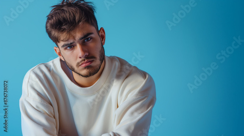 Man in white sweatshirt seated on blue background photo