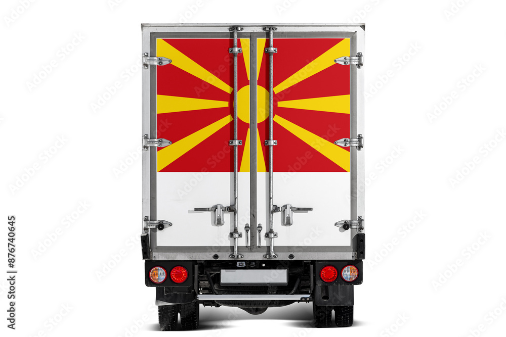 A truck with the national flag of Mazedonien depicted on the tailgate drives against a white background. Concept of export-import, transportation, national delivery of goods A truck with the national flag of Mazedonien depicted on the tailgate drives against a white background. Concept of export-import, transportation, national delivery of goods