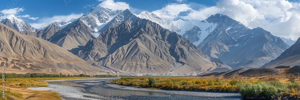 Obraz premium Scenic River Valley with Snow-Capped Peaks: Majestic landscape view of river valley surrounded by snowy mountains, serene natural beauty