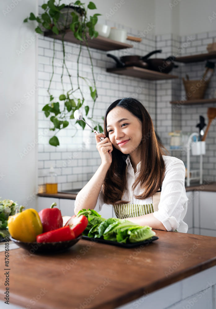 Image of young asian woman in apron preparing salad or food in the kitchen at home. Image of young asian woman in apron preparing salad or food in the kitchen at home.