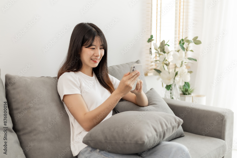 Woman sitting using smartphone on sofa inside home. Woman sitting using smartphone on sofa inside home.