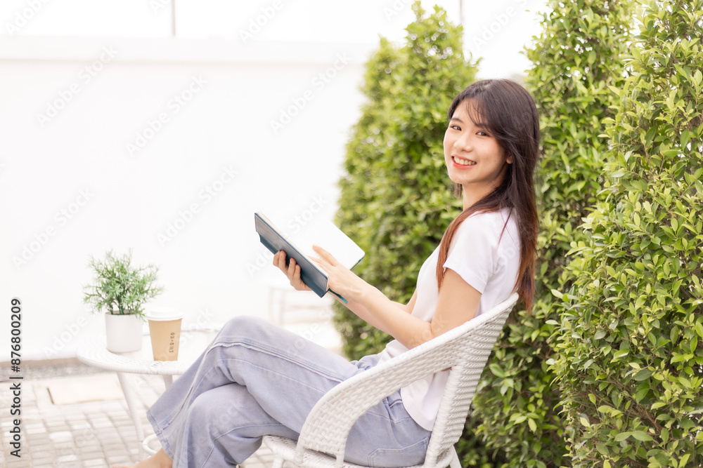 Obraz premium A woman relaxes in the garden, reads a book, talks on the phone, takes a selfie in her backyard.