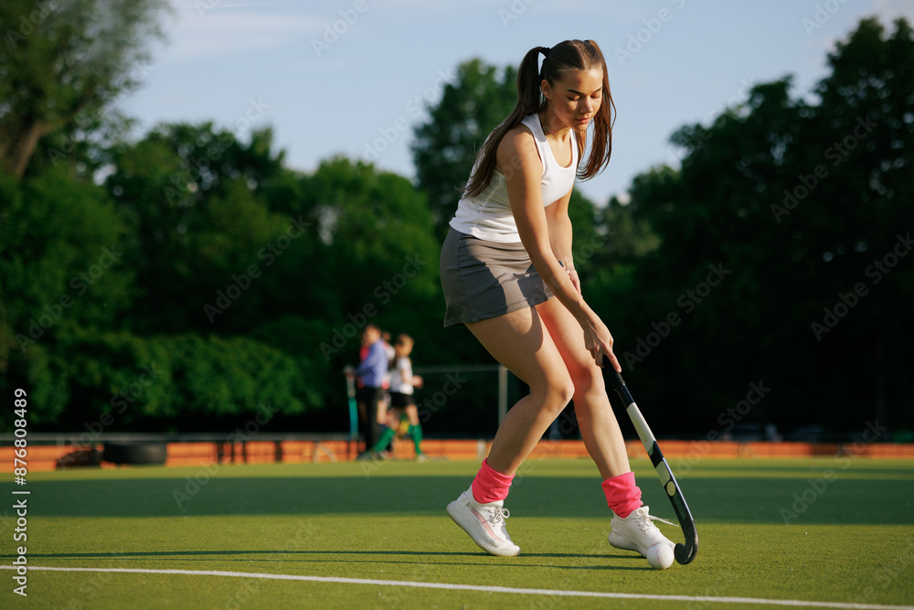 Fototapeta premium girl hockey player plays field hockey on a sunny day, the hockey player hits the ball with a stick