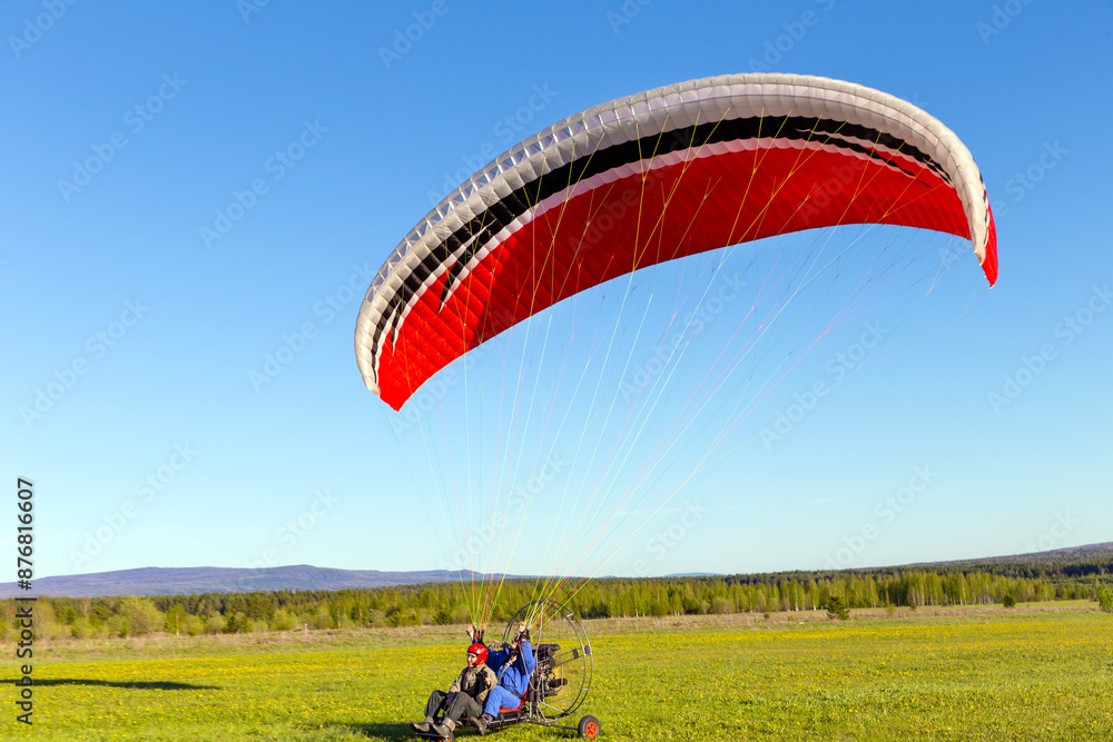 Couple paraglider flight. Two athletes take off using motor, propeller and a wing parachute Couple paraglider flight. Two athletes take off using motor, propeller and a wing parachute
