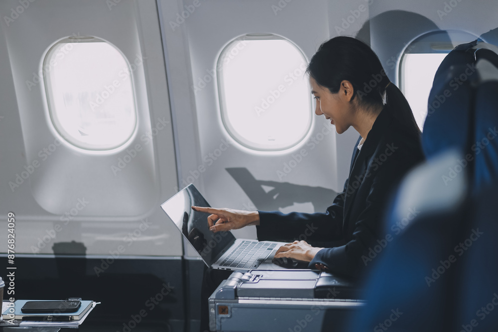 A successful asian businesswoman or female entrepreneur in formal suit in a plane sits in a business class's seat and uses a tablet computer during flight A successful asian businesswoman or female entrepreneur in formal suit in a plane sits in a business class's seat and uses a tablet computer during flight