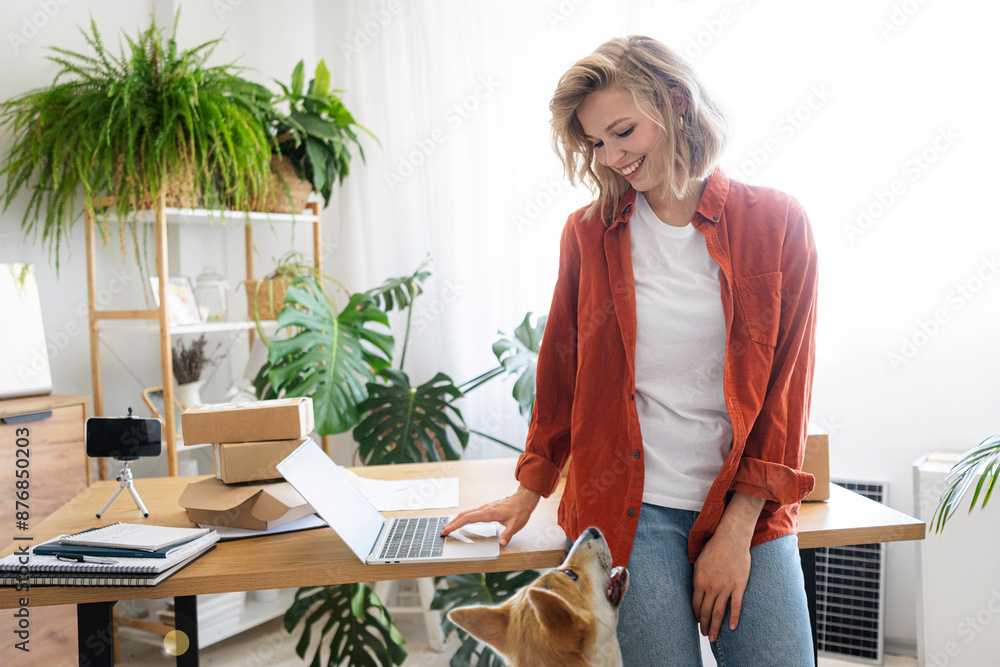 Smiling freelancer looking at dog with laptop at desk in home office Smiling freelancer looking at dog with laptop at desk in home office