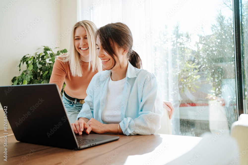Happy colleagues with laptop discussing at table Happy colleagues with laptop discussing at table