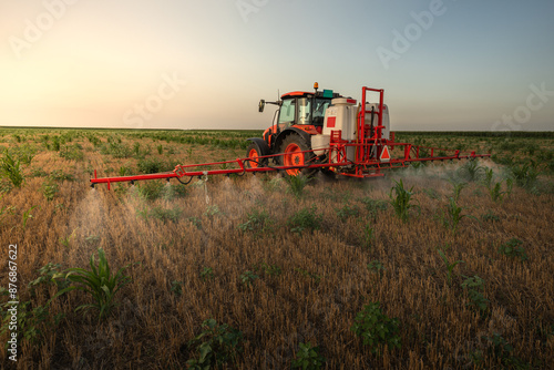 Tractor sprays field with pesticides in summer