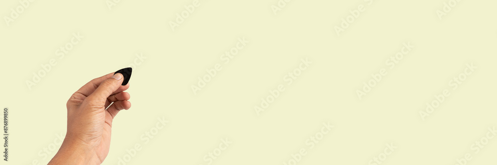 Black male hand holding a USB charger plug isolated on light green background Black male hand holding a USB charger plug isolated on light green background