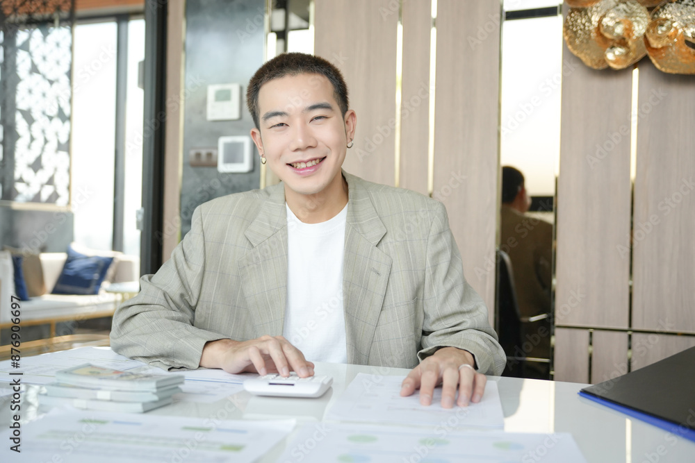Smiling young Asian businessman in modern office. handsome asian man happy and friendly while working success job Smiling young Asian businessman in modern office. handsome asian man happy and friendly while working success job