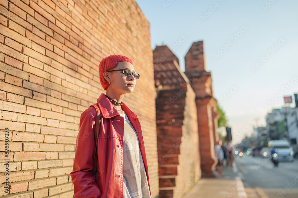 Naklejka premium Gen z girl leather fashion with punk Asian woman tourist of local city Southeast Asia travel trendy pink hairstyle young female punk traveler walking around in town