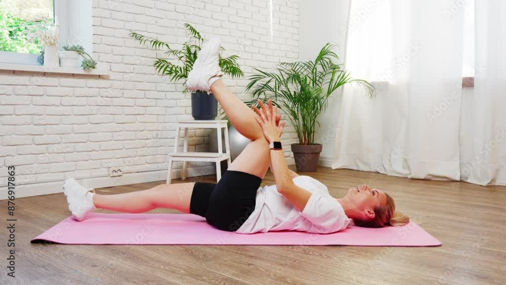 Woman Stretching Leg On Pink Mat In Home Studio Woman Stretching Leg On Pink Mat In Home Studio