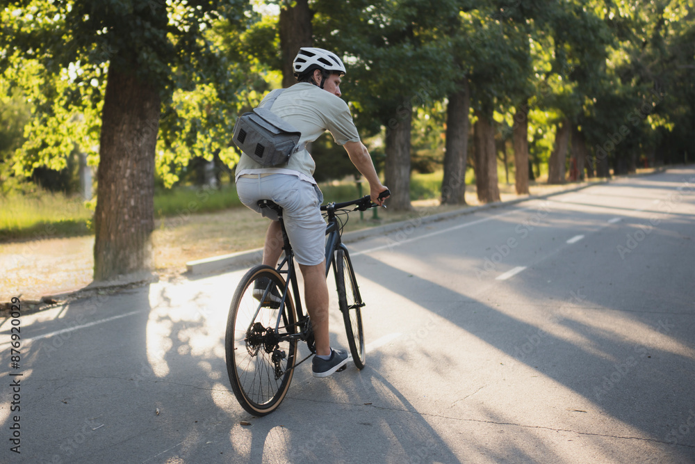 bicycle courier rides on a bike path in the city, wearing a helmet and carrying a small delivery bag bicycle courier rides on a bike path in the city, wearing a helmet and carrying a small delivery bag