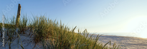 Obraz na płótnie Banner showing a beautiful wide beach on the Baltic Sea at sunset. Grasses on the dune in the foreground. Slajszewo, Choczewo, Poland w salonie