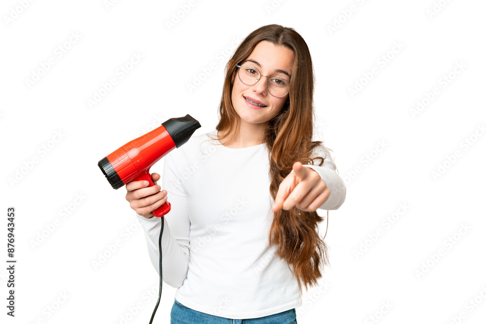 Teenager girl holding a hairdryer over isolated chroma key background points finger at you with a confident expression