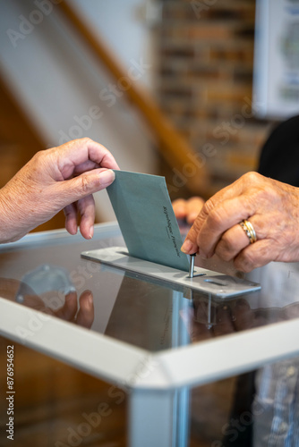 vote en république française, enveloppe glissée dans une urne transparente et ouverte  avec un clapet par un assesseur