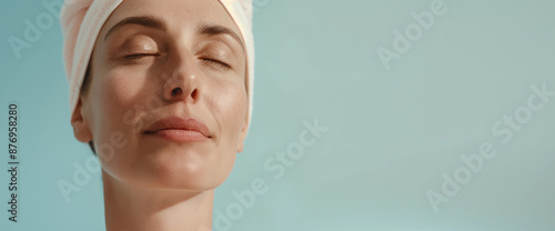 Studio portrait of clean beautiful woman drying off hair in towel turban, blue background 