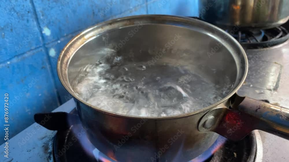 Hot boiling water in silver pot on kitchen stove at home Hot boiling water in silver pot on kitchen stove at home