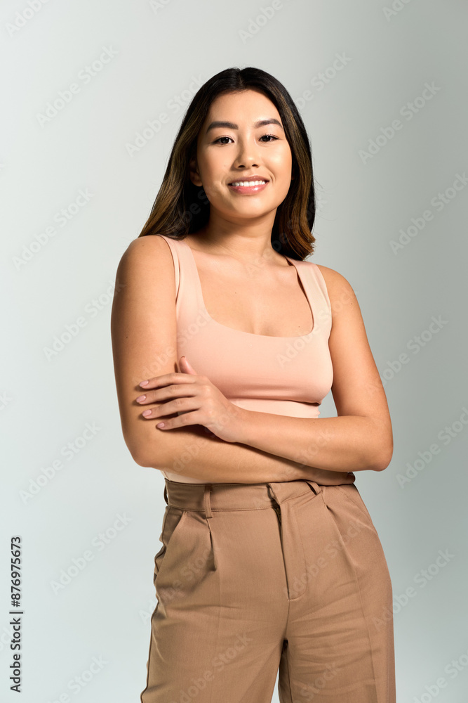 A woman with long dark hair smiles and stands with her arms crossed in front of her. A woman with long dark hair smiles and stands with her arms crossed in front of her.