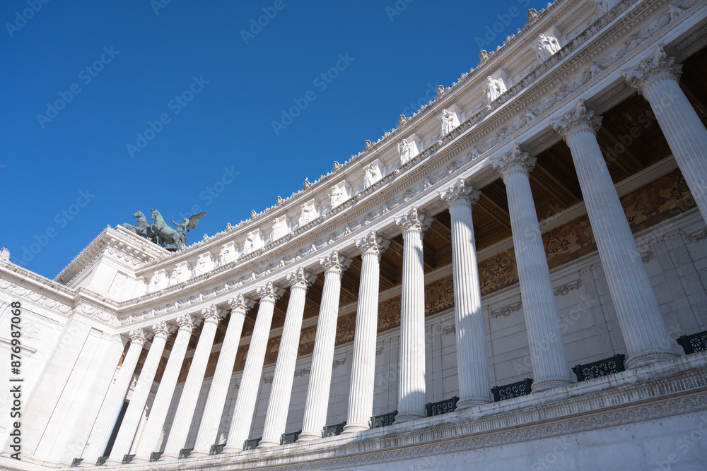 A low-angle view of the Vittoriano in Rome, showcasing its intricate white marble columns and decorative architectural details. Rome, Italy A low-angle view of the Vittoriano in Rome, showcasing its intricate white marble columns and decorative architectural details. Rome, Italy