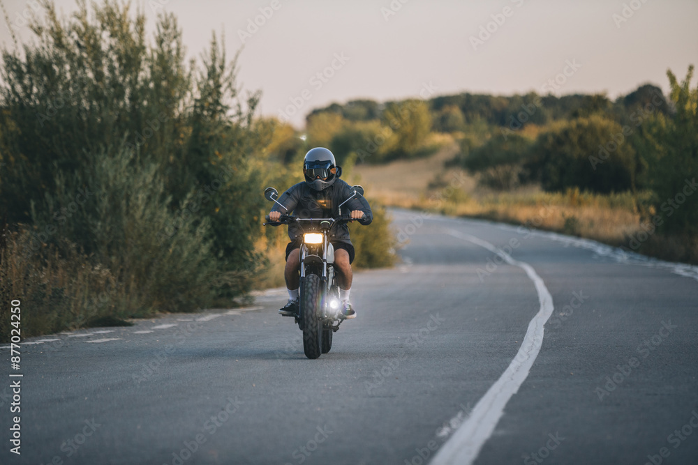 A biker rides his cafe racer motorcycle at sunset. A biker rides his cafe racer motorcycle at sunset.