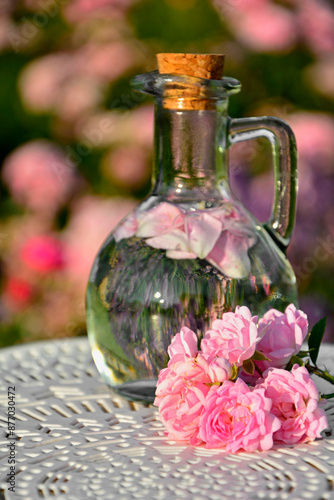 woda różana w szkalnej butelce z korkiem, woda aromatyzowana płatkami róży w butelce, rose water in a glass bottle, water flavored with rose petals in a bottle, Rose water in a glass bottle 