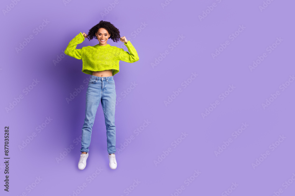 Full body photo of attractive young woman jump show biceps dressed stylish green clothes isolated on violet color background Full body photo of attractive young woman jump show biceps dressed stylish green clothes isolated on violet color background