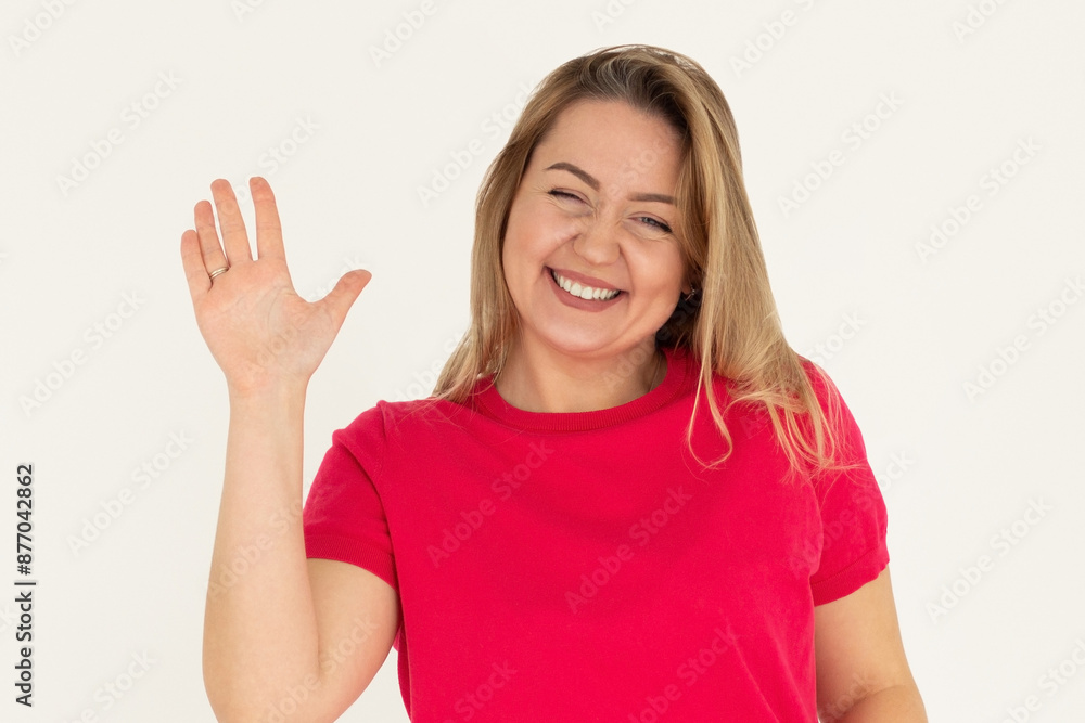 Cheerful friendly girl saying hello, winking and smiling, waving hand at camera, say hi and greet you, standing against white background Cheerful friendly girl saying hello, winking and smiling, waving hand at camera, say hi and greet you, standing against white background