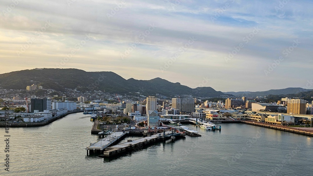 Scenic view of a coastal city with mountains in the background and a clear sky in Sasebo Scenic view of a coastal city with mountains in the background and a clear sky in Sasebo