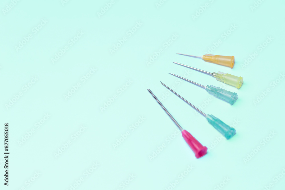 A row of five syringes with different colored tips. The syringes are lined up on a blue background A row of five syringes with different colored tips. The syringes are lined up on a blue background