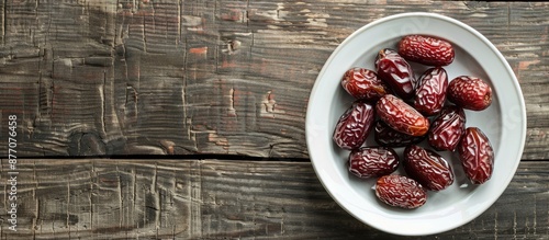 Dates fruit displayed on a white dish atop a wooden surface, perfect for Ramadan and Islamic celebrations, featuring ample copy space image. photo