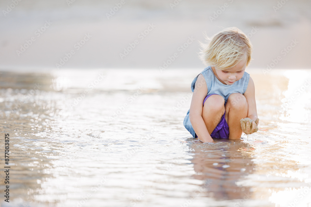 Child playing in shallow water on Gold Coast beach in golden afternoon light Child playing in shallow water on Gold Coast beach in golden afternoon light