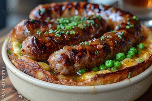 A dish of toad in the hole, with sausages baked in a Yorkshire pudding batter, served with peas and onion gravy.  photo