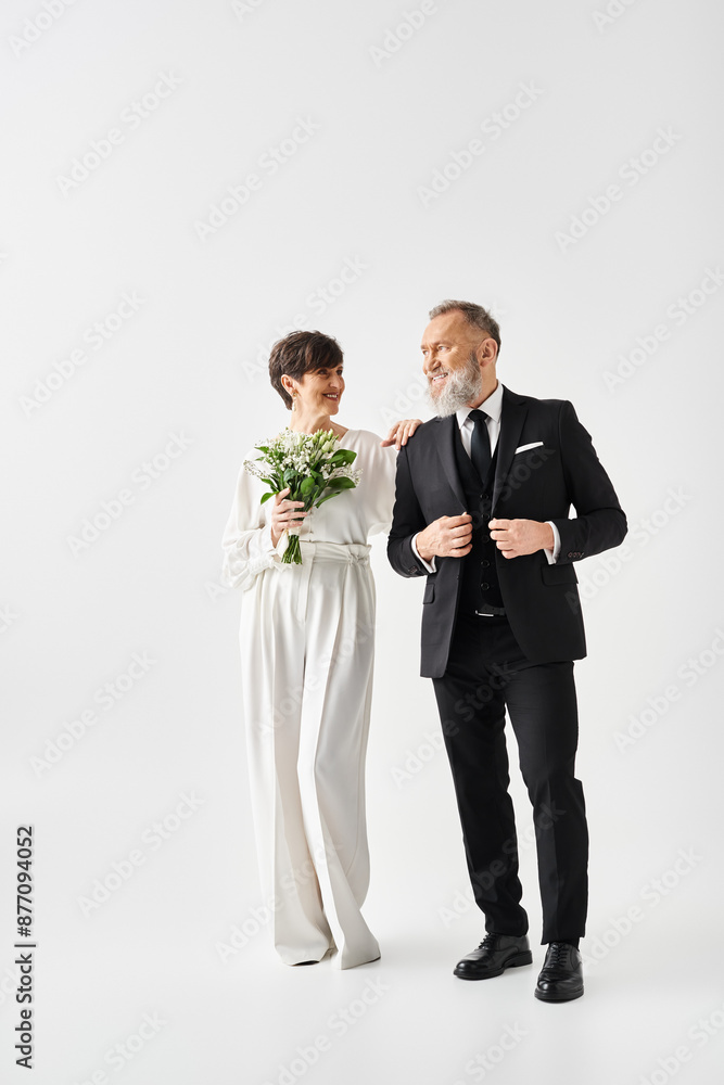 A middle-aged bride and groom in wedding attire celebrating their special day in a studio setting. A middle-aged bride and groom in wedding attire celebrating their special day in a studio setting.
