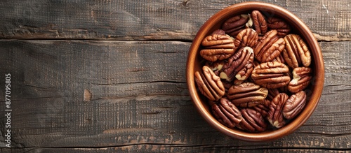 Top view of a dish with shelled pecan nuts on a wooden surface, with room for text in the image.