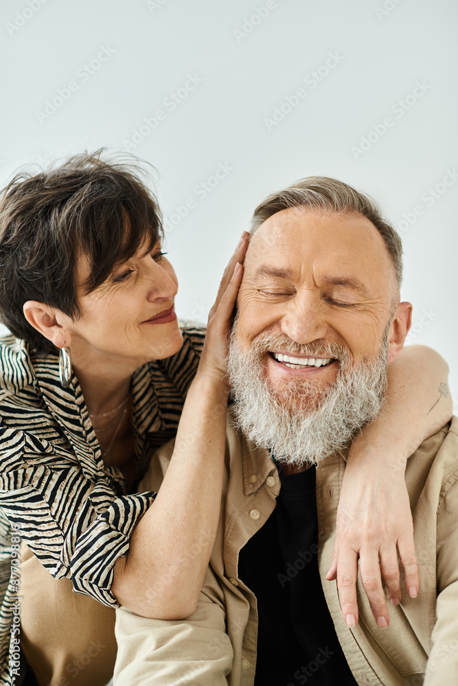 A middle-aged man and woman in stylish attire sit closely together, exuding a sense of connection and companionship. A middle-aged man and woman in stylish attire sit closely together, exuding a sense of connection and companionship.
